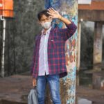 a man wearing a face mask standing next to a pole